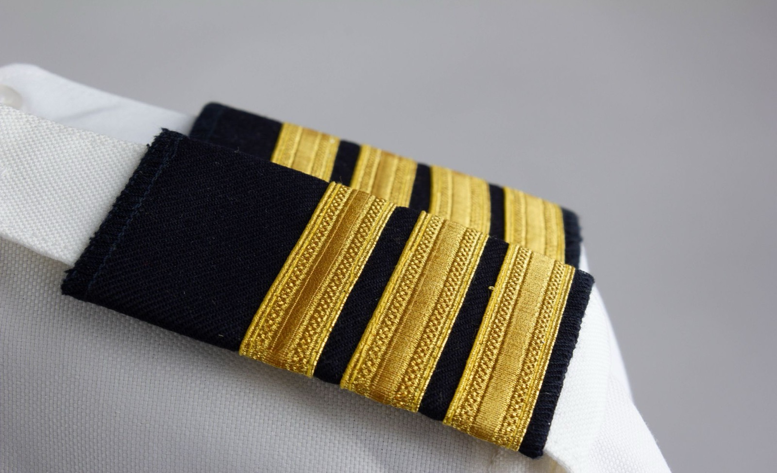 Gold four-bar captain epaulettes on the shoulder of a white shirt