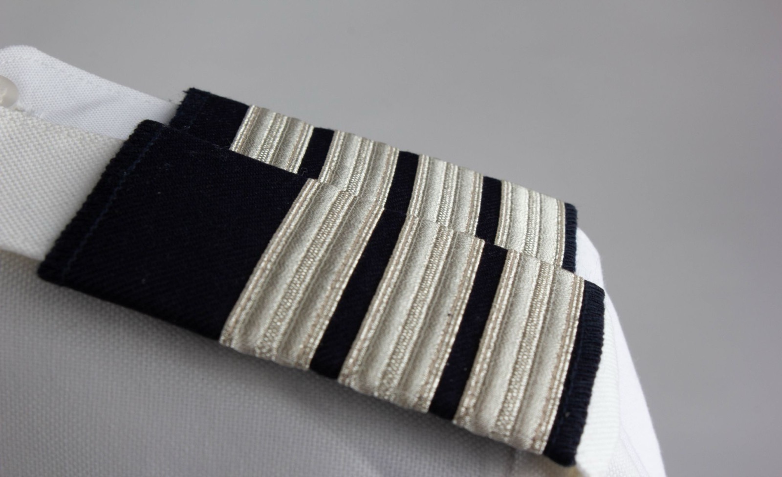A silver-striped epaulette slide on the shoulder of a white uniform shirt