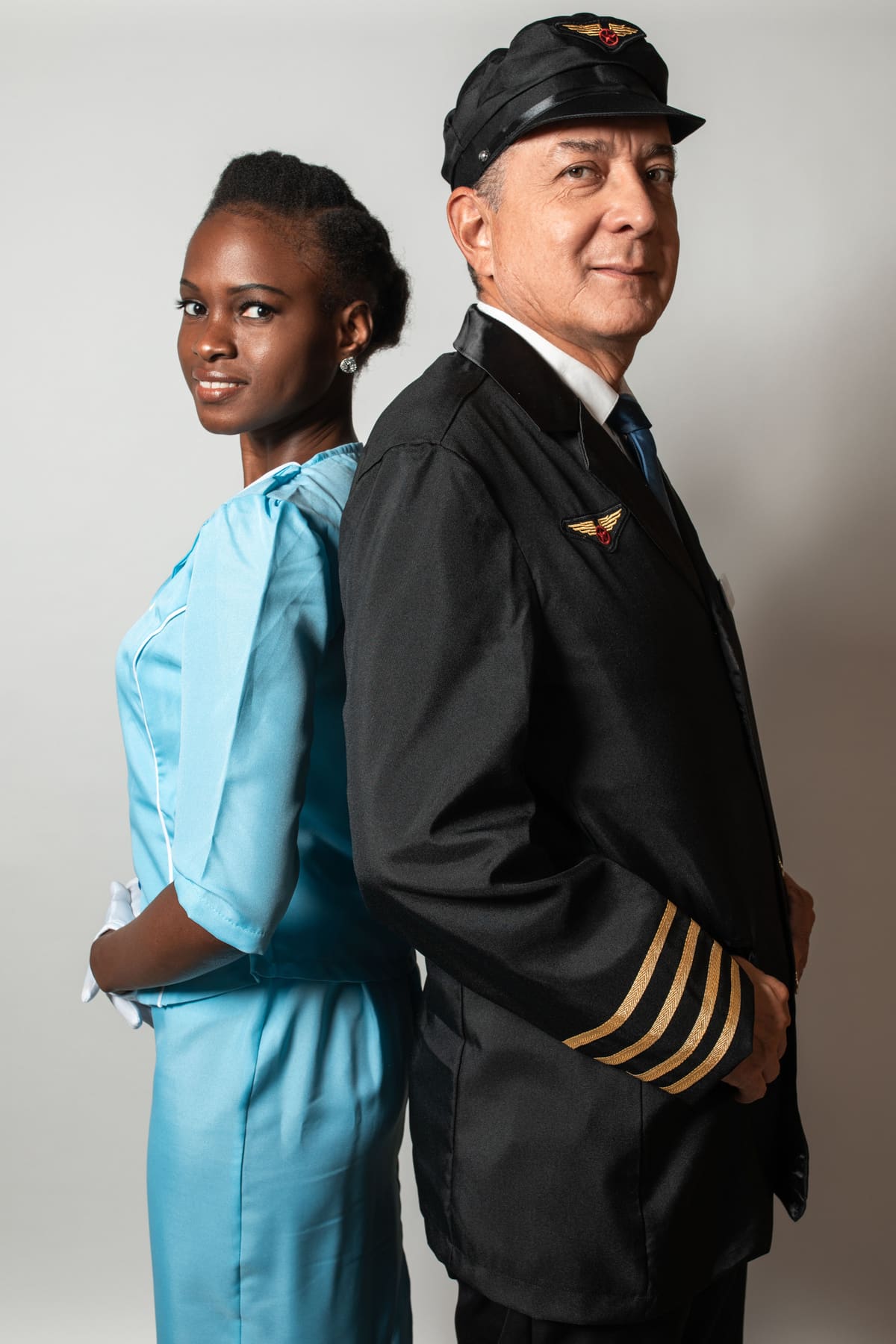 A flight attendant and a pilot standing back to back in tailored aviation uniforms
