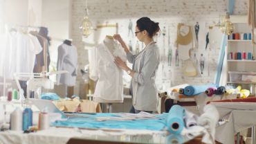 A tailor measuring fabric during a uniform fitting